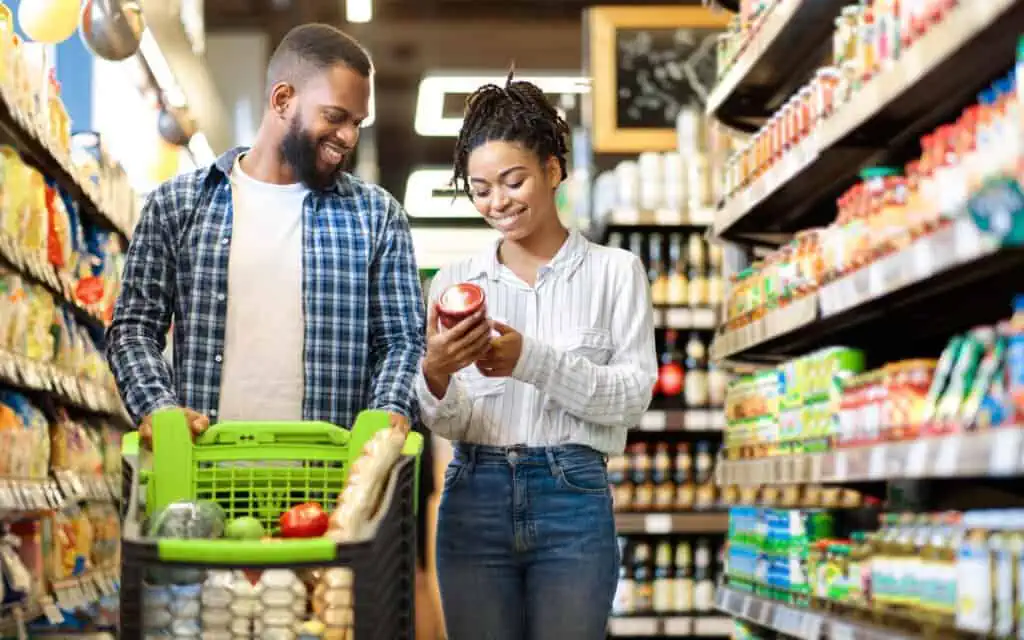 african family buying food supermarket shop walking pushing cart choosing groceries together happy customers black couple grocery store empty space text